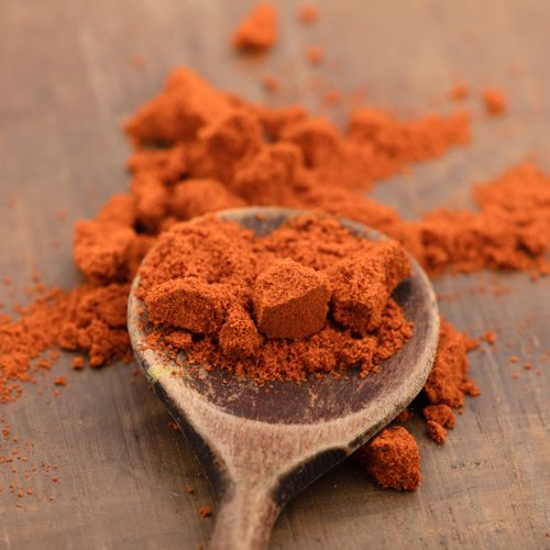 Ground paprika on a wooden spoon