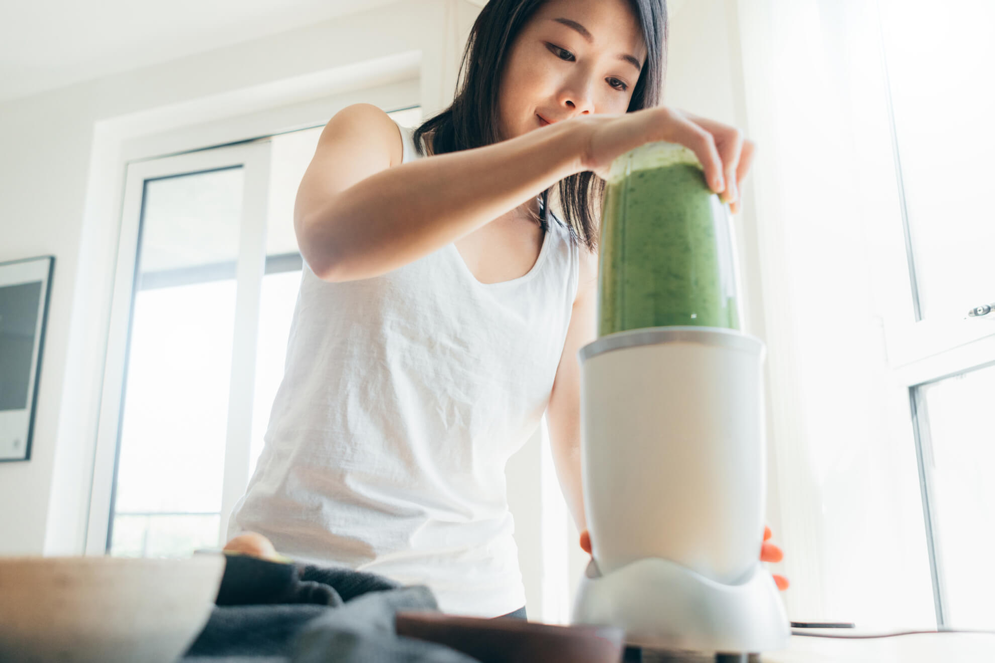 Young woman making green smoothie